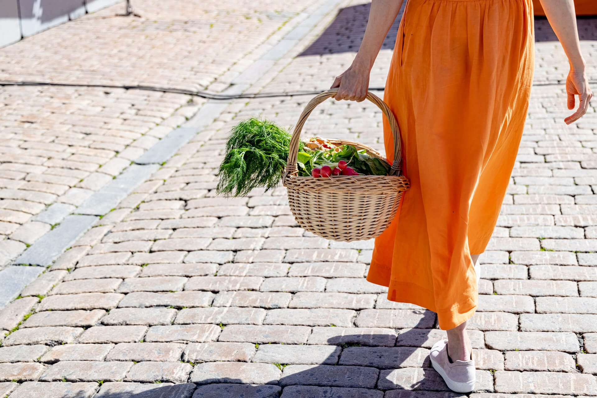 En kvinna bär en korg med grönsaker