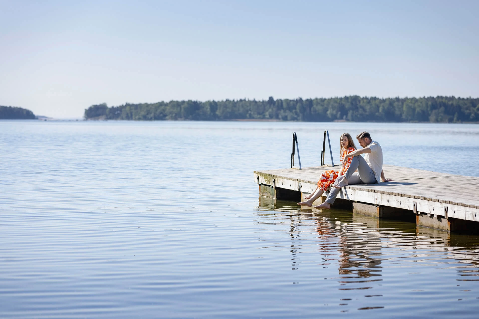 Dekorativ bild av kvinna och man som sitter på en brygga