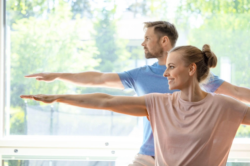 Dekorativ bild på en Kvinna och man som sträcker ut armarna i en yoga-pose