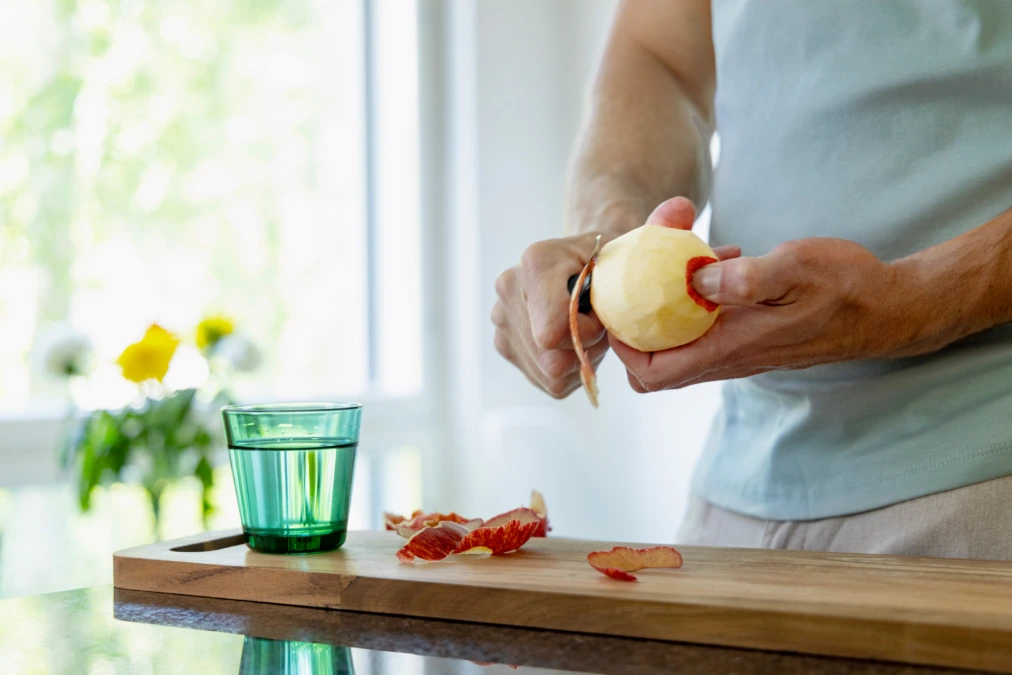 Man skalar ett äpple på en skärbräda