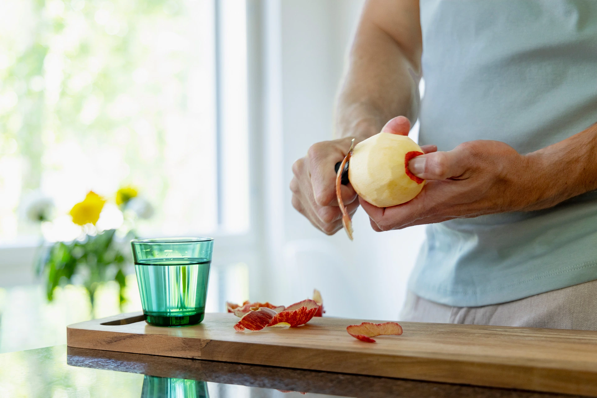 Man skalar ett äpple på en skärbräda