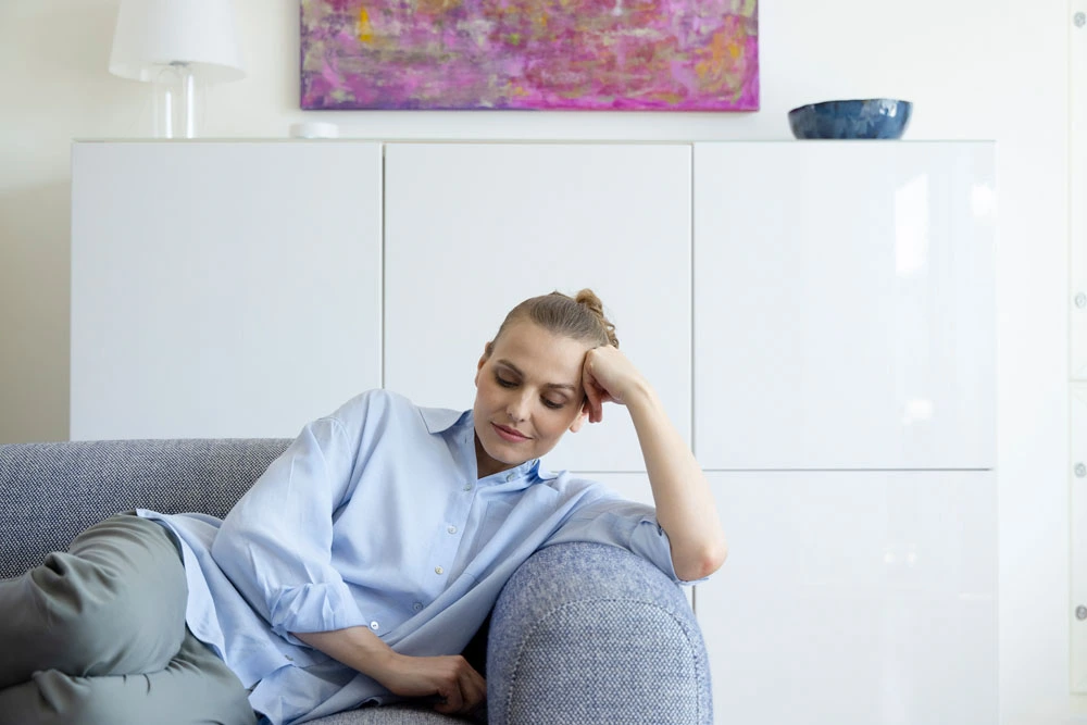 Illustrativ bild på en trött kvinna som ligger i soffan